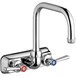 A silver and chrome Chicago Faucets wall-mounted sink faucet with red and silver knobs.