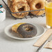 A plate of Greater Knead gluten-free poppy seed bagels and orange juice on a table.