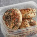 A Greater Knead gluten-free everything bagel in a plastic container with sesame seeds and black specks.
