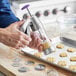 A person using a Wilton cookie press to make cookies.
