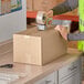 A person packing a Lavex Kraft corrugated shipping box.