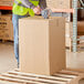 A man in a yellow vest standing on a pallet with a Lavex kraft cardboard box.