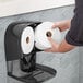 A hand holding a Tork Universal toilet paper roll.