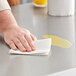 A hand wiping a counter with a Tork Universal paper towel.