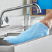 A person washing a sink with a blue Tork food service cleaning towel.