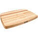 A John Boos maple wood cutting board with a grooved and reversible surface on a table.
