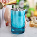A person pouring a cocktail into a Barfly blue stirring / mixing glass.