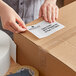A person packing a box with a Lavex white thermal transfer label on it.