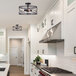 A kitchen with white cabinets and a Canarm Malene matte black semi-flush mount light.