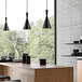 A professional kitchen with black Canarm Rocco pendant lights above a counter.