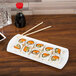 A CAC white china fashion platter with sushi on a table.