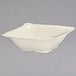 A white square bowl with a handle on a white surface.