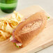 A sandwich on a Schar gluten-free sandwich roll with chips on a wooden board.