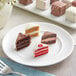 A white plate with an assortment of Cuisine Innovations Petit Fours including chocolate and red cake slices.