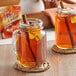 A couple of mugs of Alpine spiced apple cider with cinnamon sticks and oranges.