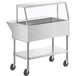 A stainless steel ServIt ice-cooled food table on casters with an angled glass sneeze guard.