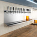 A Regency stainless steel wall mount beer drip tray with beer taps above it.