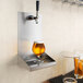 A Regency stainless steel wall mount beer drip tray with a glass of beer on it.