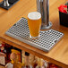 A glass of beer on a Regency stainless steel surface mount beer drip tray.