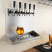 A glass of beer on a Regency stainless steel wall mount drip tray shelf.