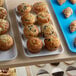 A Cambro white fiberglass market tray of muffins on a shelf in a bakery display.