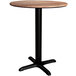 A Lancaster Table & Seating Excalibur round wooden table with a black base.