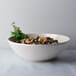 A close-up of a white Thunder Group Passion Pearl melamine bowl filled with beans and herbs.