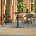 A Lancaster Table & Seating Yukon Oak table with 2 chairs on an outdoor patio.