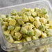 A plastic container filled with frozen green and yellow Pitaya Foods organic avocado pieces.