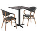 A Lancaster Table & Seating Paladina table with two black French bistro chairs.
