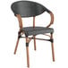 A black French bistro arm chair with a wooden seat and back.