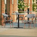 A Lancaster Table & Seating Versilla table with chairs outside on a patio.