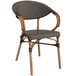 A Lancaster Table & Seating wicker chair with wooden legs and a black cushion.
