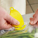A person using a yellow CrewSafe Viper Pro bag opener to cut a plastic bag.