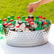 A hand holding a bottle of soda in a Tablecraft stainless steel beverage tub filled with ice.