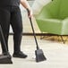 A woman using a Lavex lobby broom to sweep the floor.