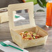 A close-up of a World Centric rectangular eco-friendly to-go container with a PLA window filled with food.
