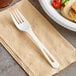 A World Centric compostable fork on a napkin next to a plate of food.
