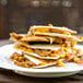 A stack of quesadillas with Barvecue Plant-Based Vegan Wood-Smoked Carnitas on a white plate.