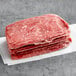 A stack of Original Philly Cheesesteak Co. seasoned beef sandwich steaks on a white surface.
