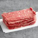 A stack of Original Philly Cheesesteak Co. seasoned beef sandwich steaks on a white surface.