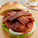 A bacon sandwich with lettuce on a bun.