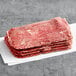 A stack of Original Philly Cheesesteak Co. marinated beef sandwich steaks on a white surface.