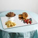 A Cal-Mil rectangular mirror tray with pastries and fruit on a table.