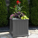 A graphite gray Mayne Cape Cod planter with flowers and plants in it.