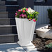 A white Mayne Aberdeen planter with pink and white flowers on steps.