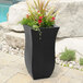 A black Mayne Valencia planter with flowers in it.