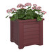 A Mayne cranberry red planter with flowers in it.