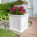 A white Mayne Cape Cod planter with pink flowers.