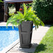 A Mayne Fairfield graphite gray planter with a fern in it on an outdoor patio table.
